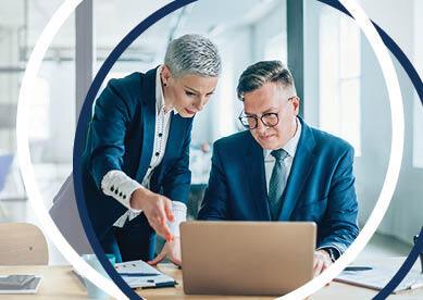 Business woman and man looking at lap and discussing in office conference room